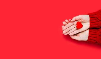 Flatlay composition. Females hands holding red heart on red background. Close-up. Top view. Place for text. photo