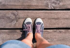 Female legs in polka dot sneakers on on a wooden pontoon. Top view. Copy space. photo