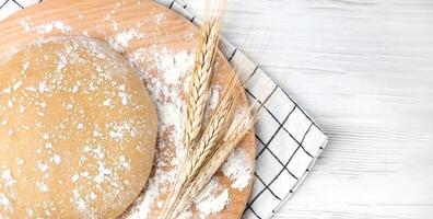 Fresh dough on a wooden board on the table. Baking bread or biscuits. Close-up.Copy space. Top view. photo