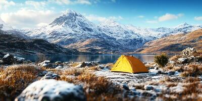 Camping tent at scenic wild campsite on a lake shore with mountain range in winter background photo