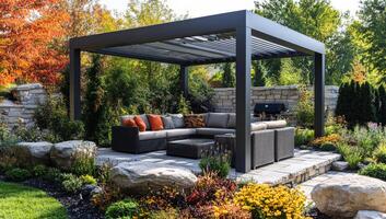 A large patio with a black gazebo and a stone wall. The patio is filled with comfortable furniture and colorful flowers photo