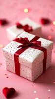 A white box with a red bow on top of it. The box is decorated with red hearts photo