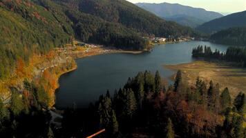 Aerial view of Lake Spitzingsee in Bavarian Alps on sunny autumn day reveals clear blue water reflecting vibrant fall colors. Luftaufnahme vom Spitzingsee in den Schlierseer Bergen Bayerischen Alpen. video