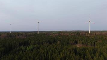 Antenne Aussicht von Wind Bauernhof Turbinen einstellen oben im Landschaft mit Wald. produzieren Leistung mit Energie von Natur. einarbeiten Technologie in Umgebung von Natur. wolkig Himmel. Elektrizität Produktion. video
