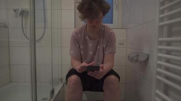 Woman is addicted to internet, sits on toilet for long hours and uses smartphone. Female sits long hours on WC and scrolls internet and gets hooked on social media. Everyday online dependency. video