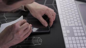 Close-up of male hand preparing and installing screen protector on smartphone. Top view of attaching protective sheet to smart phone display. Tempered glass shield protector. Maintenance and repairing video
