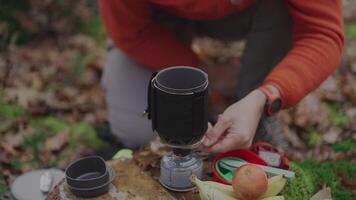 Hiker twists power control switch and ignites gas burner with spark by pressing piezo spark button on handheld cooking system for a camping trip in the fall. Cooking equipment for the expedition. video