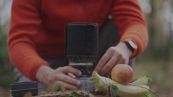 Hiker twists power control switch and ignites gas burner with spark by pressing piezo spark button on handheld cooking system for a camping trip in the fall. Cooking equipment for the expedition. video