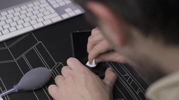 Close-up of male hand preparing and installing screen protector on smartphone. Top view of attaching protective sheet to smart phone display. Tempered glass shield protector. Maintenance and repairing video