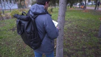 The man has lost his best friend a husky puppy. The owner posts an ad banner about the missing dog on the trees in the park. Missing pet banner. Dog search reward. Stole a pet. Lost Siberian Husky. video