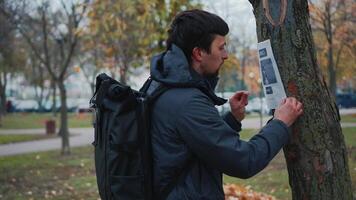 The man has lost his best friend a husky puppy. The owner posts an ad banner about the missing dog on the trees in the park. Missing pet banner. Dog search reward. Stole a pet. Lost Siberian Husky. video