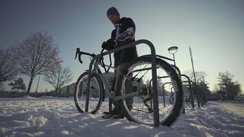 Security and antitheft lock for a bicycle. Man cyclist unlocks cycle in an outdoor bike parking lot in a European city in Germany. Guy unlocking bicycle in open rack in winter in snowy weather. video