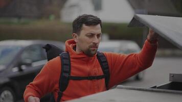 Man throws trash in clear garbage bag with biologicals food waste into garbage can near home before go to work in Europe. Garbage sorting. Containers for waste separation. Environmental conservation. video