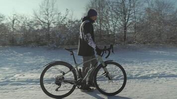 Man bicyclist walks through park pushing bicycle beside him because slippery path covered with snow in sunny winter weather in Europe. Cyclist walking with his bicycle through snowy park in Germany. video