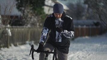Navigation, GPS positioning, routing, offline map in a smartphone. Male cyclist stopped while cycling in winter in snow to check messages and direction of the journey. Bicycle rides in snowy weather. video