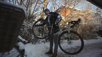 Cleaning dirt and snow off the bicycle using a brush outside the house before taking it home. Man brushes wheels of bicycle with scrub brush out front house in winter. Snow and cycling. video