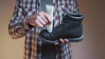 Man prepares black suede boots before fall and winter by applying a protective and nourishing suede cream while holding boot in his hands. Topic winter shoe care. Theme maintenance of autumn boots. video