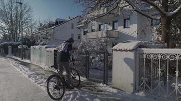 Commuting by bicycle in winter. Man cyclist returns home in snowy, sunny, freezing weather and opens wicket going into yard in Germany. Cyclist arrives outside at home and going to be parking cycle. video
