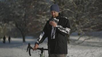 Cyclist uses smartphone to find road, building route on map, navigation in winter in snowy, sunny weather in Germany. People, sports, active lifestyle and modern technology. GPS navigation on phone. video