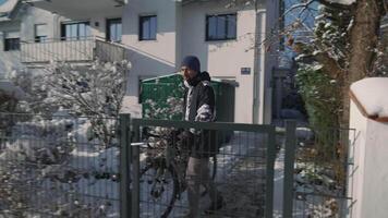 Male bicyclist leaves courtyard of house with bicycle in sunny winter weather with snow. Commuter leaves house by opening the wicket in Europe in winter. Daily use of the bicycle in all weathers. video