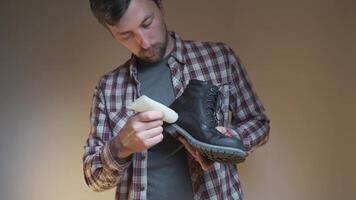 Man prepares black suede boots before fall and winter by applying a protective and nourishing suede cream while holding boot in his hands. Topic winter shoe care. Theme maintenance of autumn boots. video