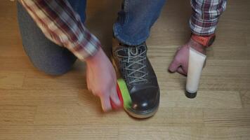 Unrecognizable man cleans brown leather boots with brush and lubricates with cream and blotting protection. Theme shoe care. Boot waxing. Outdoor boots with wax. Accessories for boot caring. video