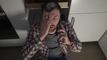 Man lost his job and feels terrible, rubbing face and drinking wine from a bottle alone on kitchen floor at home and calling on the phone and complaining to a friend. Depression, girlfriend left me. video