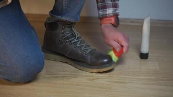 Unrecognizable man cleans brown leather boots with brush and lubricates with cream and blotting protection. Theme shoe care. Boot waxing. Outdoor boots with wax. Accessories for boot caring. video