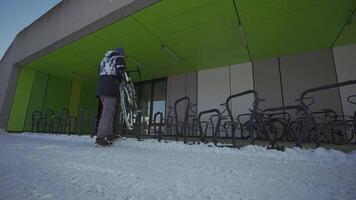 Man cyclist locks bicycle in a street parking lot in Europe in winter snowy weather. Locking bike for parking . Protecting your cycle from burglary. Commuting on a bicycle in the frost. video
