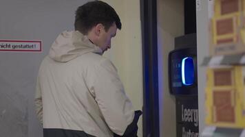 Man returns plastic bottles in the supermarket vending machine. Male refunds paid for plastic Into automatic dispenser bottles in store. Recycling machine. Receive money from machinery for plastic. video