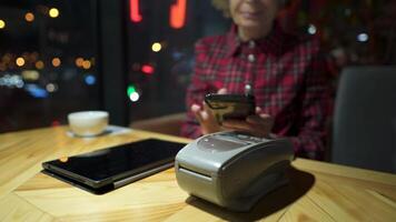 Contactless payment. Nfs payment by phone. Client of cafe or restaurant holding smartphone over electronic payment machine while using mobile app to pay. Non cash payment. NFC technology. video