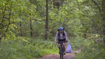 Volunteer bicyclist remove trash bags for garbage, clean up forest during bicycle ride. Save environment. Recycle waste litter rubbish garbage trash junk clean training. Picking up trash while cycling video