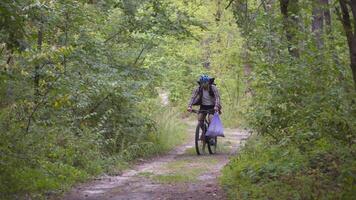 Volunteer bicyclist remove trash bags for garbage, clean up forest during bicycle ride. Save environment. Recycle waste litter rubbish garbage trash junk clean training. Picking up trash while cycling video