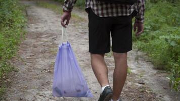 A bad man throws garbage out of a plastic trash bag in the forest. The male intruder leaves litter trash and walks away. Pollution and ecological problem, plastic recycling, pollution of nature. video