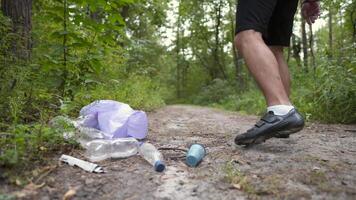 A bad man throws garbage out of a plastic trash bag in the forest. The male intruder leaves litter trash and walks away. Pollution and ecological problem, plastic recycling, pollution of nature. video