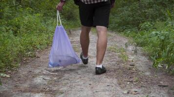 Environmental total pollution by human life products, ecological problem, global warming. Polluted forest. Bad man litters on a forest path, pours trash from a plastic bag on the ground and leaves. video