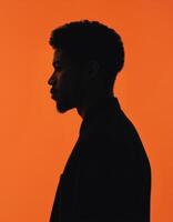 Profile Silhouette of a Man Against Orange Background photo