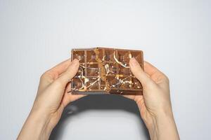 Trend Dubai chocolate with chocolate spread and kataifi broken in woman's hands. Confectionery handmade sweets, chocolatier. photo