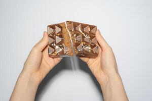 Famous Dubai chocolate with chocolate spread and kataifi filling broken in woman's hands. Confectionery handmade sweets, chocolatier. photo
