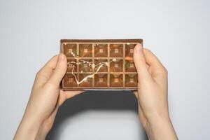 Famous Dubai chocolate with pistachio, tahini and kadaif in woman hands. Confectionery handmade sweets, chocolatier photo