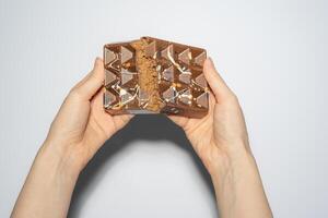 Famous Dubai chocolate with chocolate spread and kadaif broken in woman's hands. Confectionery handmade sweets, chocolatier photo