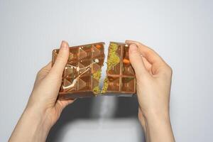Famous Dubai chocolate with pistachio, tahini and kadaif broken in woman's hands. Confectionery handmade sweets, chocolatier photo