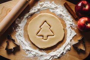 Dough on a floured board with apples, cinnamon, and cookie cutters for baking photo