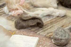 Variety of natural wool fibers and yarns displayed on a table photo