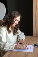Smiling Woman Writing a Letter at a Wooden Table photo