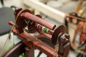 Distaff Day Wooden spinning wheel with yarn and hooks in workshop setting photo