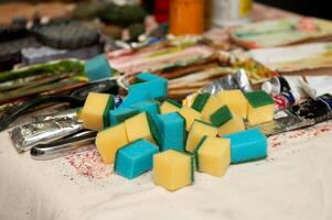 Pile of colorful cleaning sponges on a table amidst artistic supplies photo