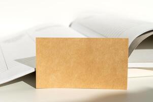 Blank Card Leaning on Open Book with Neutral Background photo