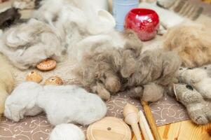 Wool fibers and tools for felting craft on patterned fabric background photo