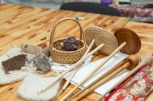 Handcrafted yarn tools and wool samples on wooden table photo